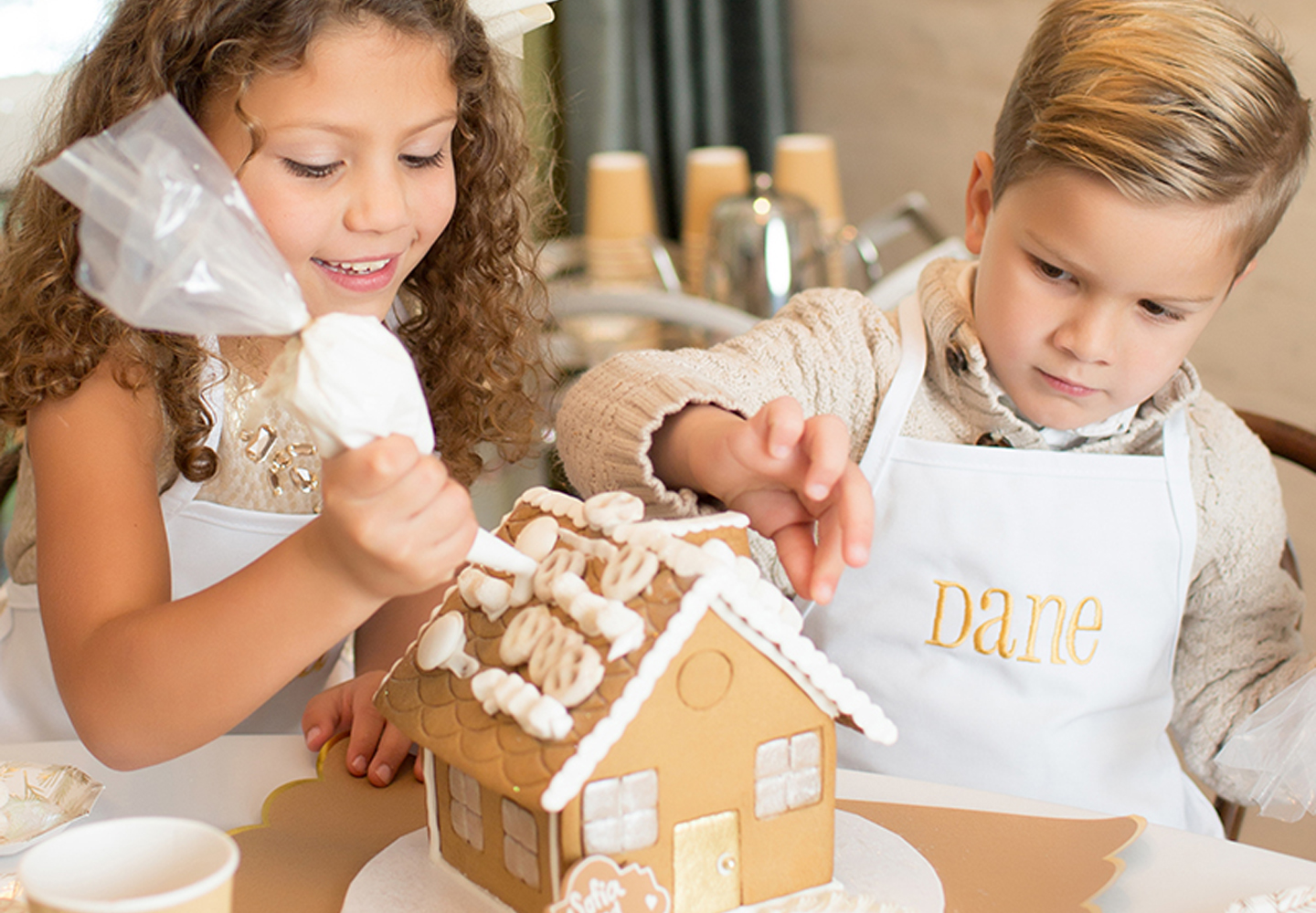Two kids decorating a gingerbread house. 