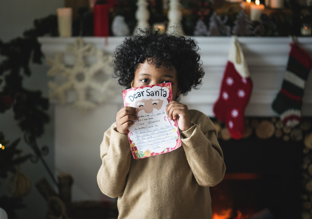 Kid with Christmas list ideas in front of his face