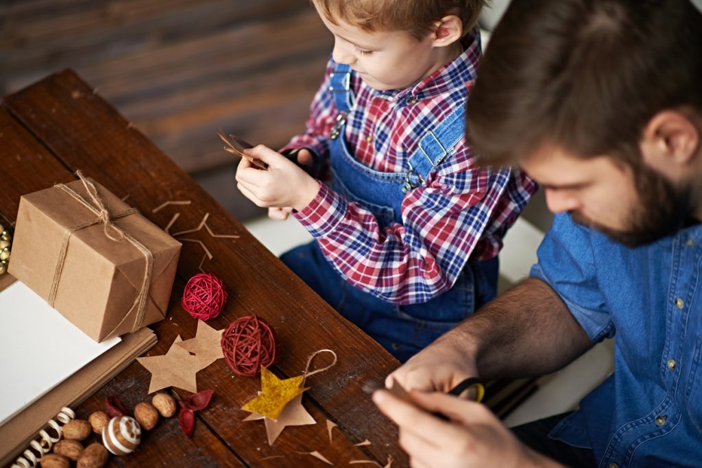 Father and son cutting paper stars gift tags.