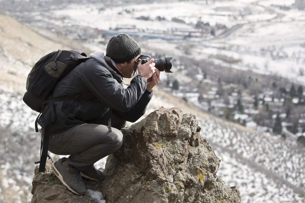 A beginner photographer looking through his viewfinder towards the mountains.
