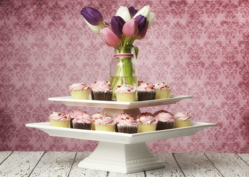 Cupcake centerpiece for birthday with pink frosted cupcakes, decorated with hearts, and tulips.