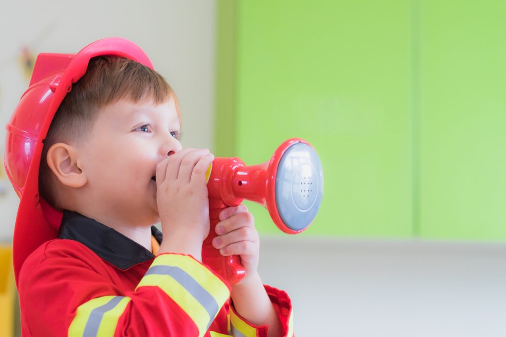 Boy dress up to fireman and use speaker at roll play for birthday party.