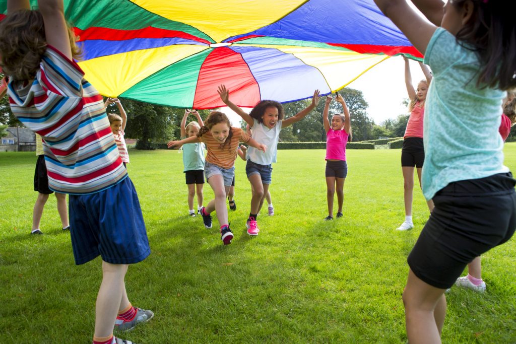 Children playing a game with a colorful Parachute.