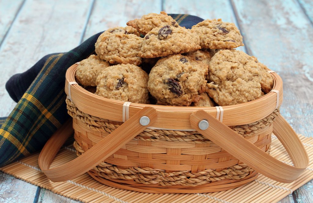 Homemade oatmeal raisin cookies in a basket on a blue rustic table.