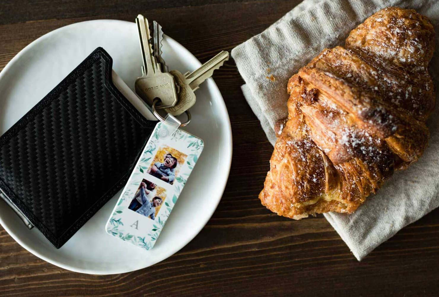 Photo keychain and wallet on a table with a croissant.