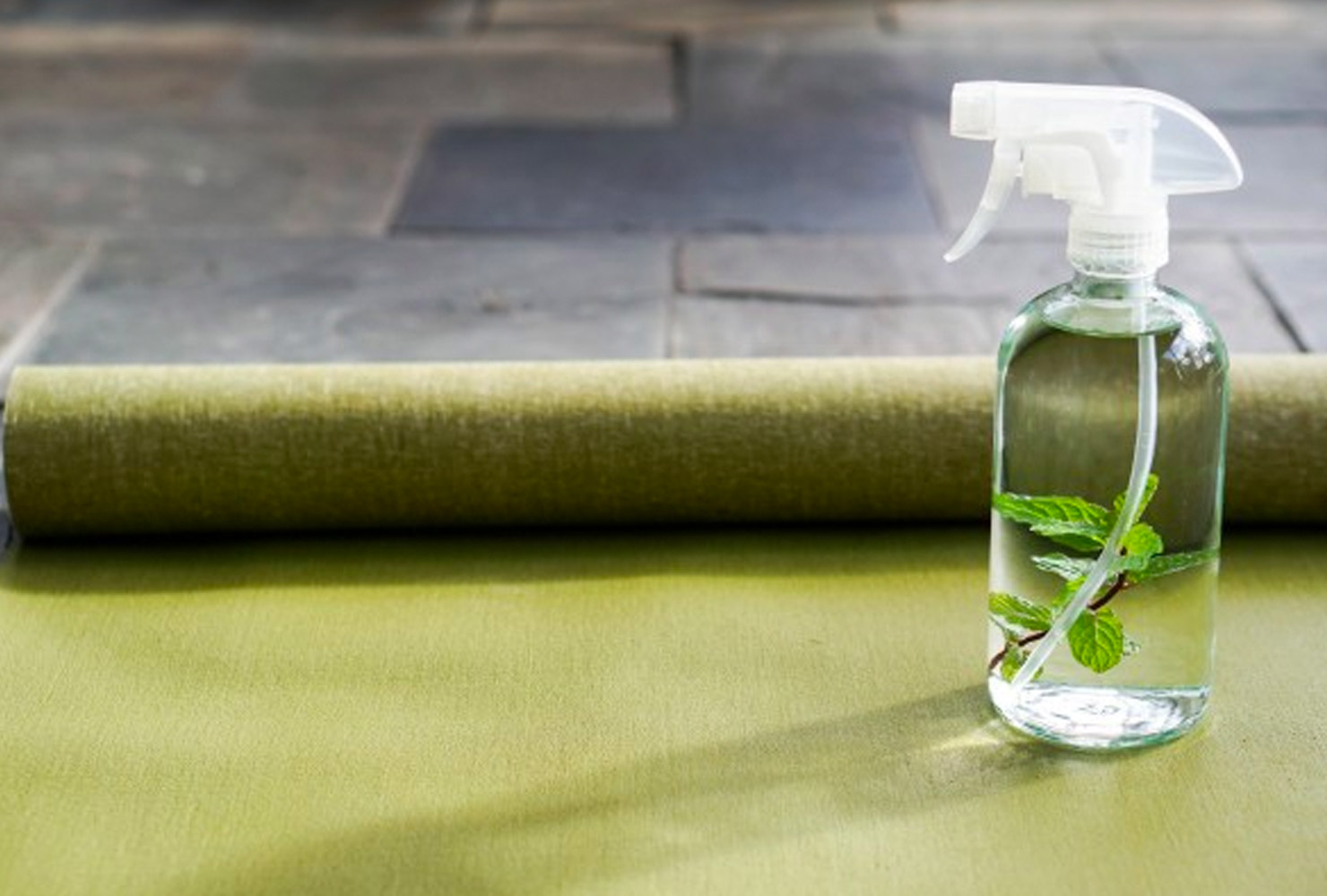 Clear spray bottle on green yoga mat.