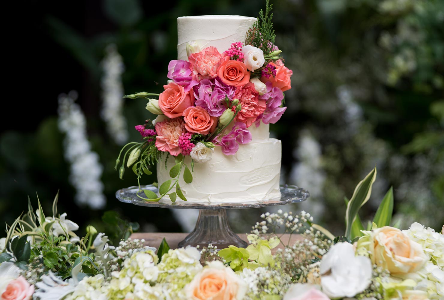 Bright pink florals on wedding cake display.