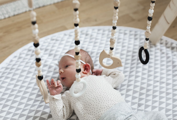 Baby lays under hanging beads