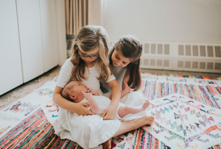 two girls holding their baby sibling