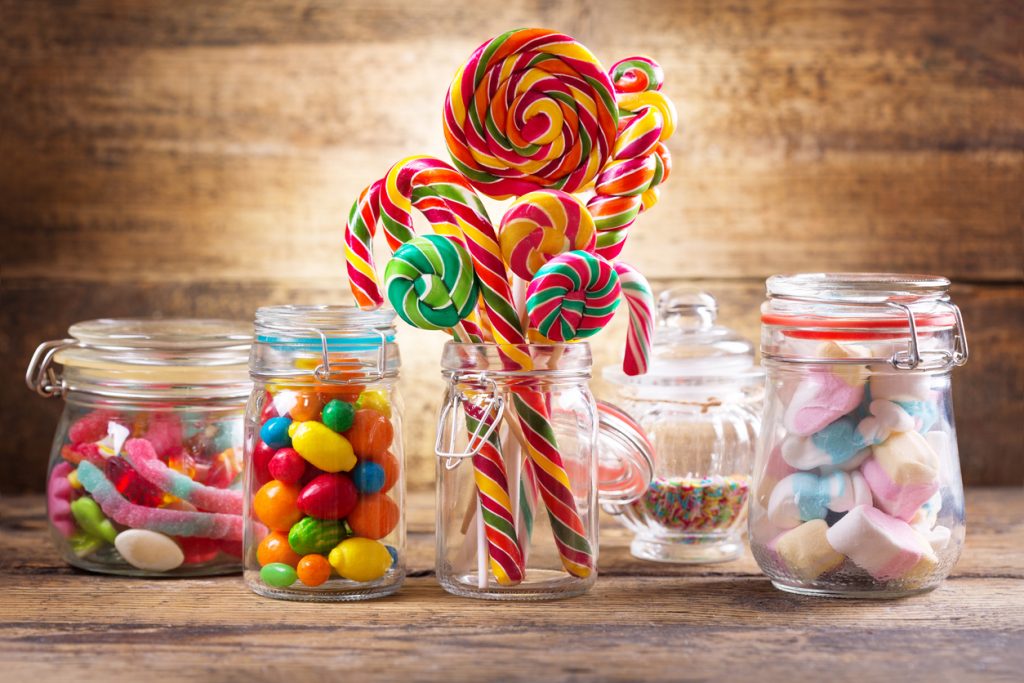 Colorful candies, jellies, lollipops, marshmallows and marmalade in a glass jars on wooden table
