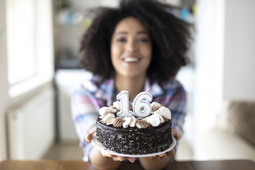 birthday girl holding a sweet 16 birthday party cake