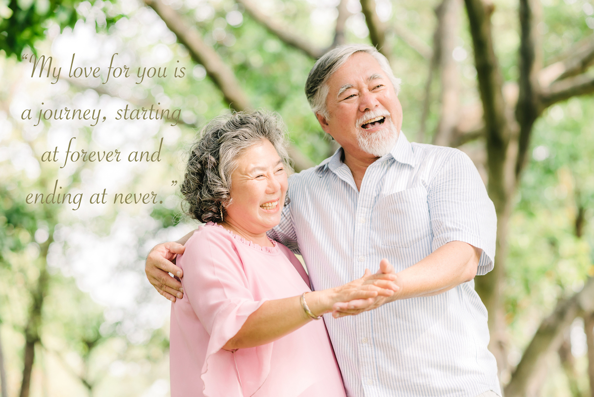 Happy senior Asian couple dancing in the park in sunny day with wedding anniversary quotes for parents overlay