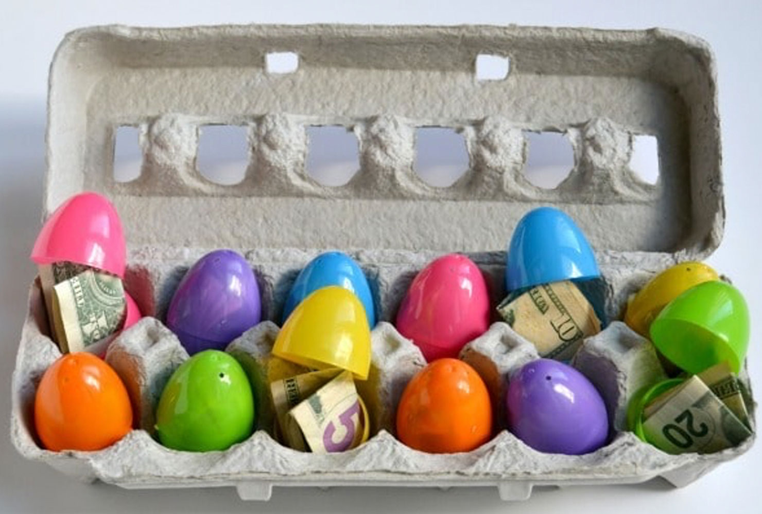 Colorful plastic eggs with money in an egg carton