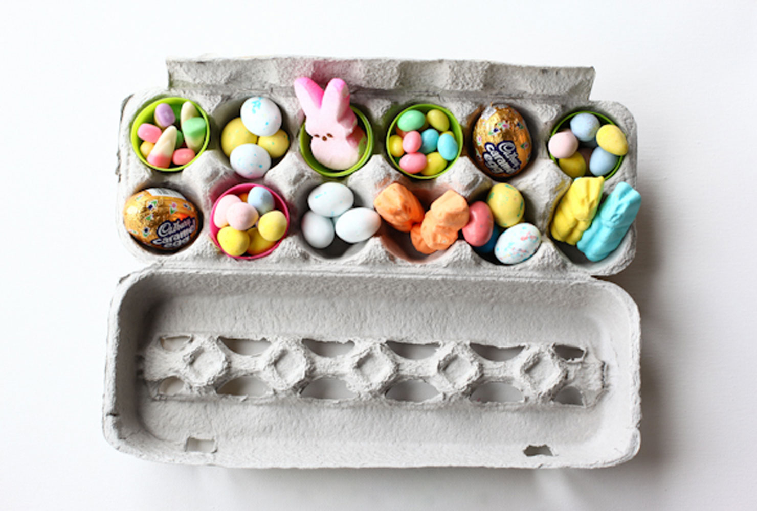 Colorful plastic eggs filled with candies in an egg carton