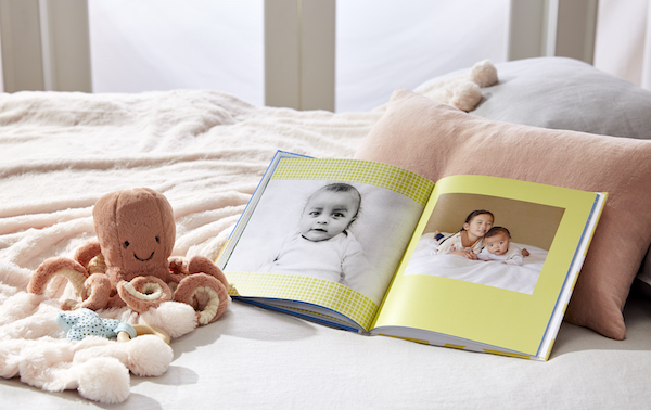 A baby photo book on a bed.