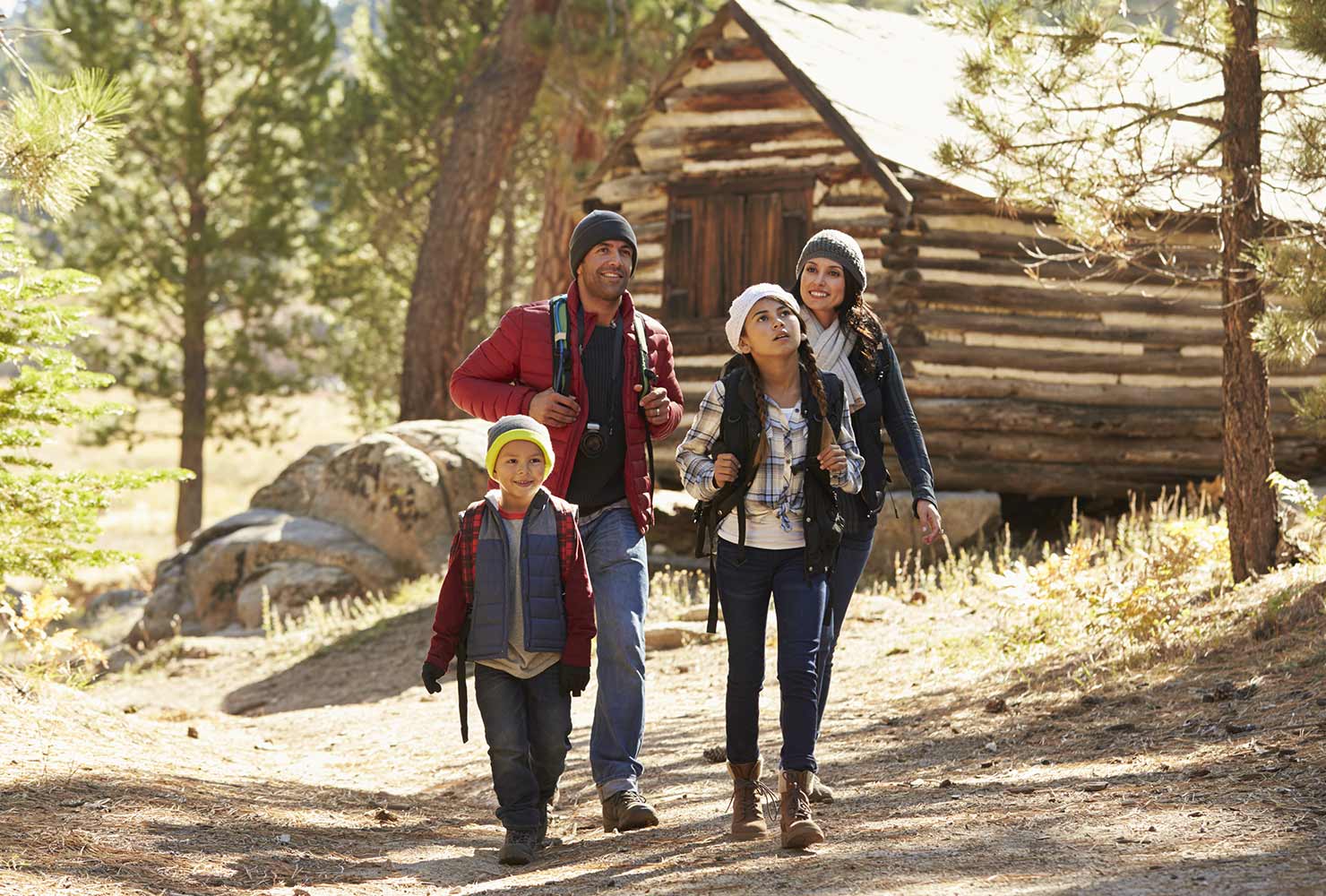 family hiking in the woods by a log cabin