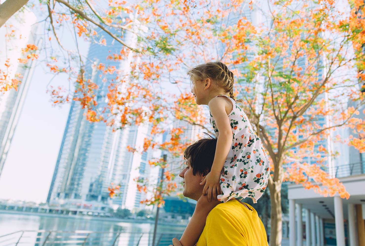 girl sitting on her dads shoulders while walking in a city