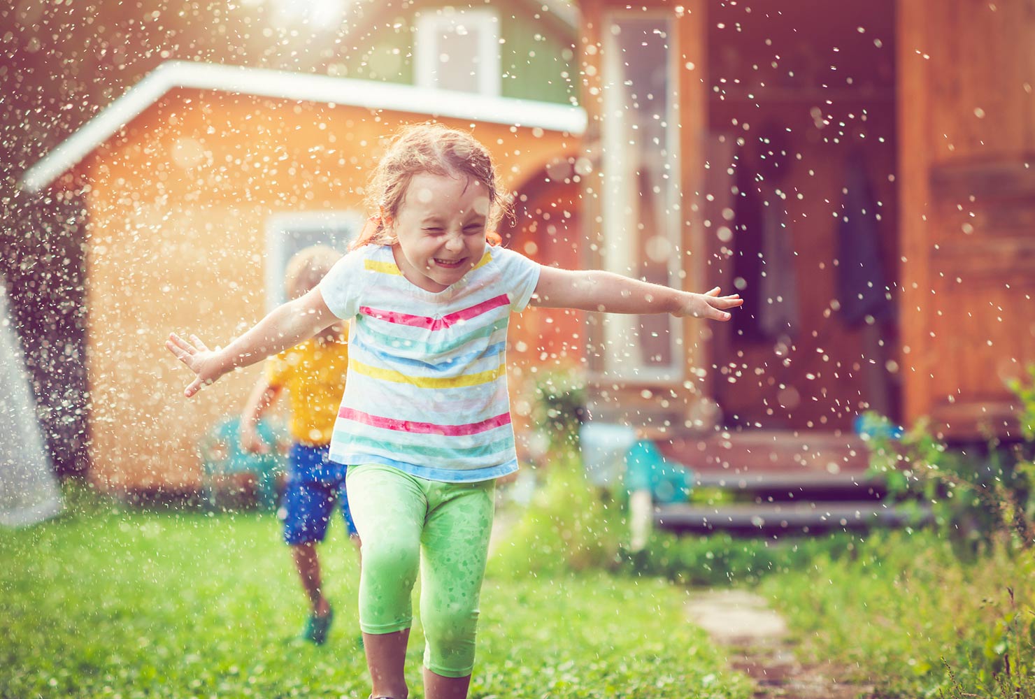 girl running through sprinkler