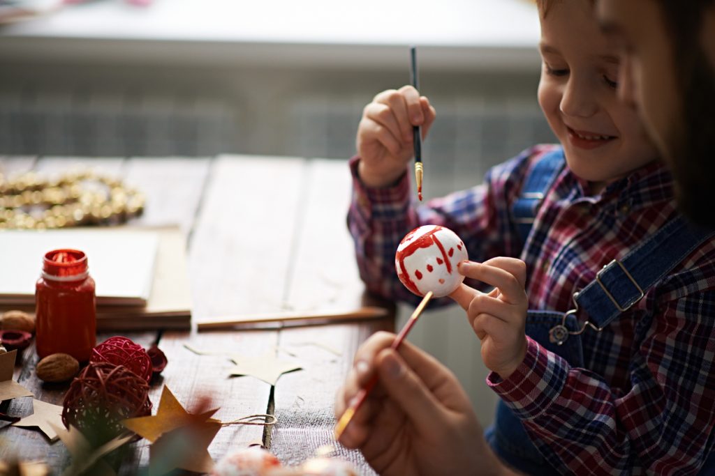 Boy showing self-painted Christmas ornament to Dad.