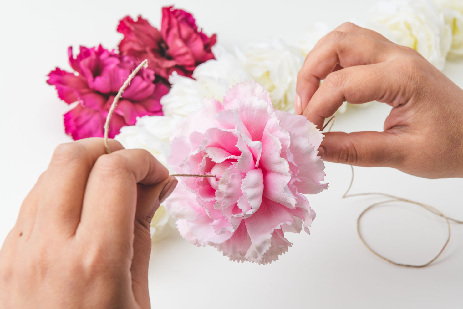 woman stringing pink flowers with twine