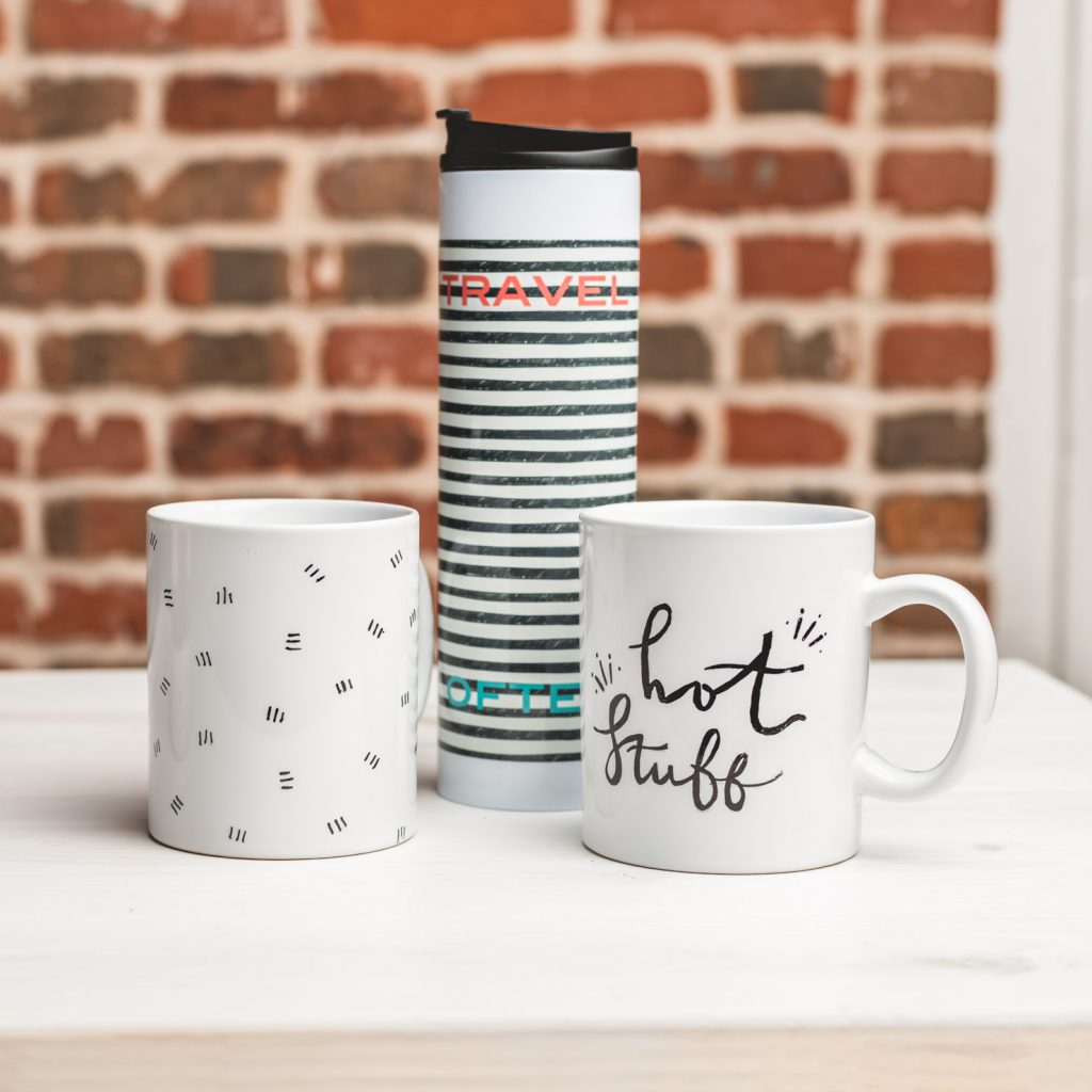 Travel mug next to two coffee mugs.