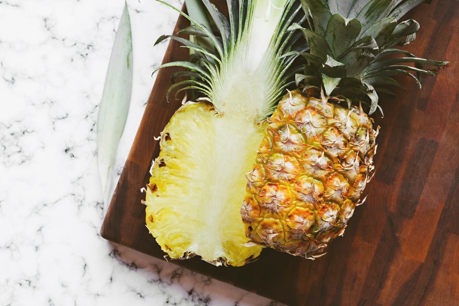 wooden cutting board with pineapple in half