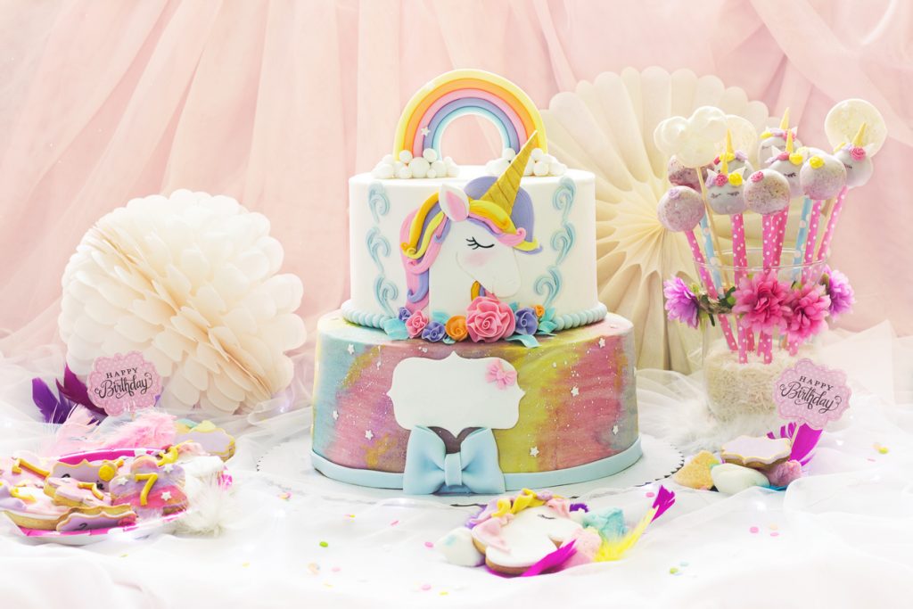 Dessert table with unicorn cake, cake-pops, sugar cookies, and birthday decoration