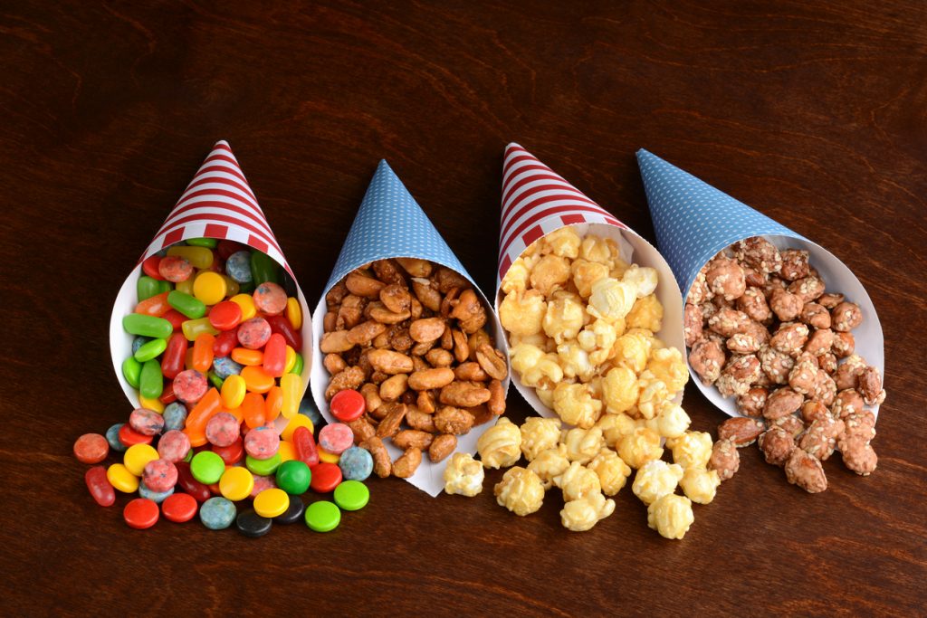Assorted candies in paper cones on a wood table top.