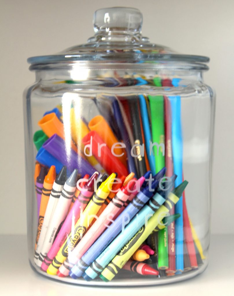 A glass jar for holding school and art supplies.