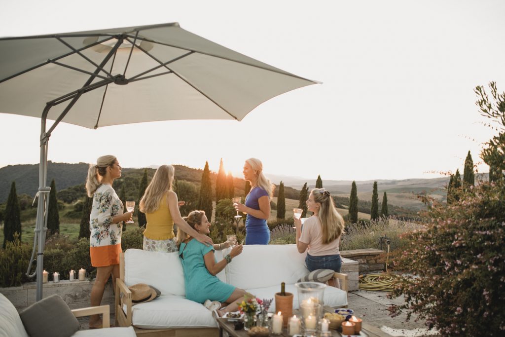 Small group of women are watching the sunset from the garden of their villa at a bachelorette party.