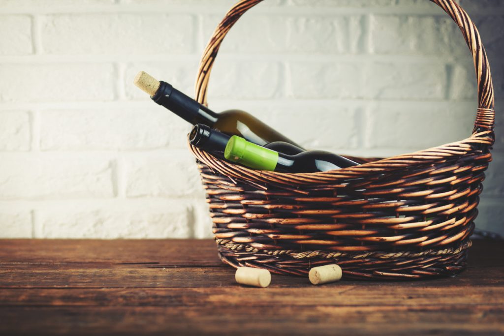 Wine bottles in basket on brick wall background.