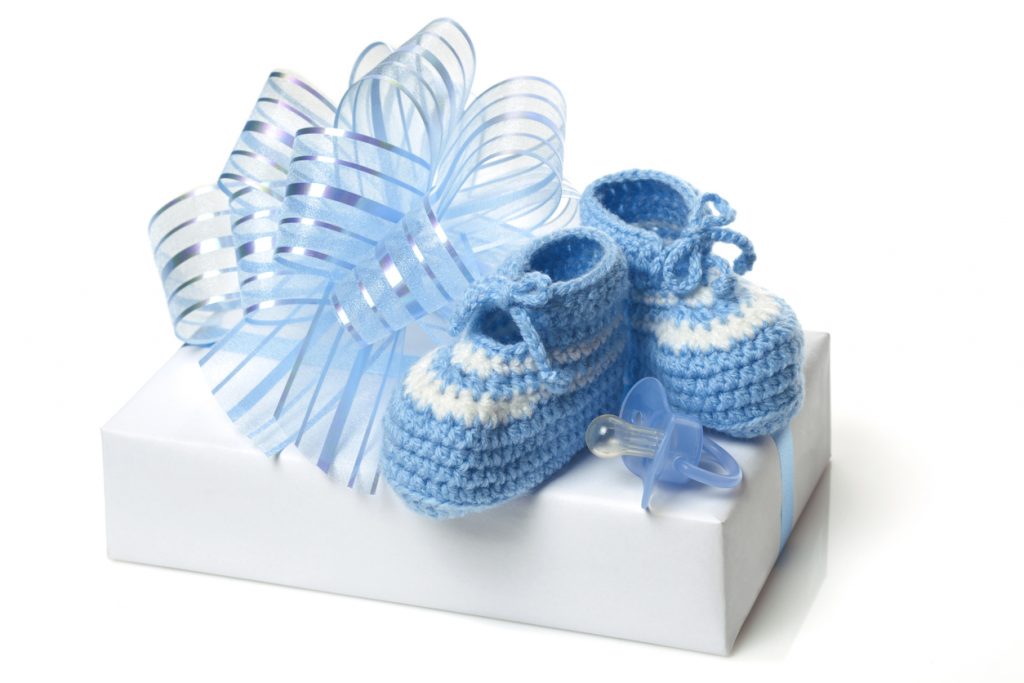 Homemade knitted baby blue booties, pacifier and present.