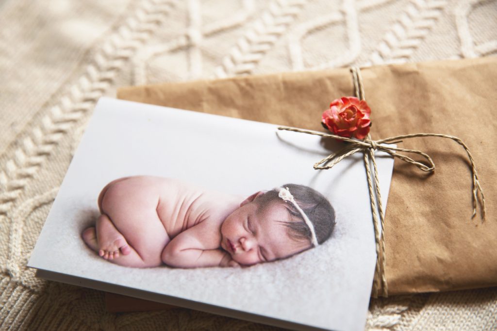 Printed greeting card with cutest sleeping newborn baby on the knitted background with gift card.