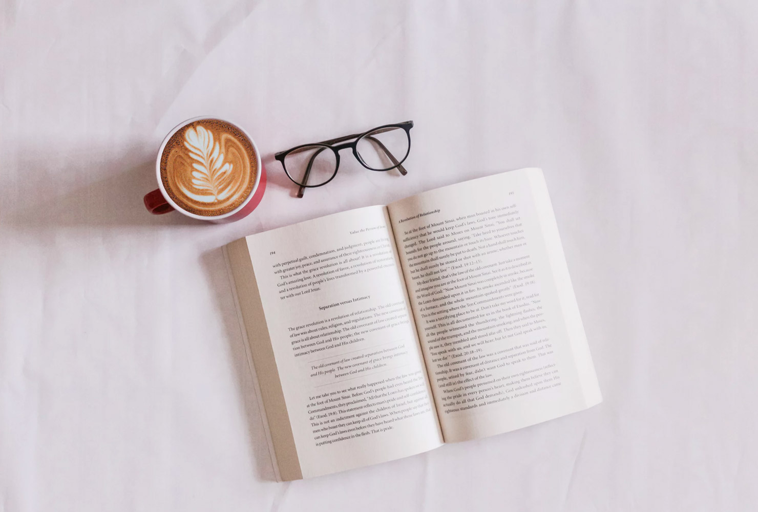 Open book with a cup of coffee and glasses.
