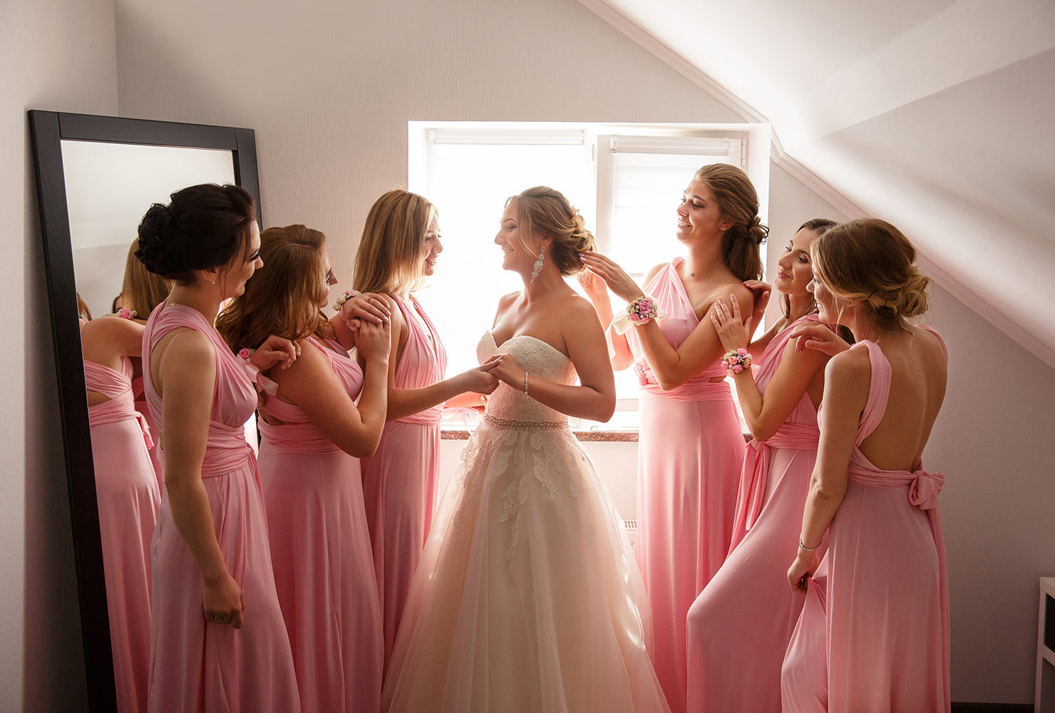 Bride surrounded by bridesmaids in pink dresses.