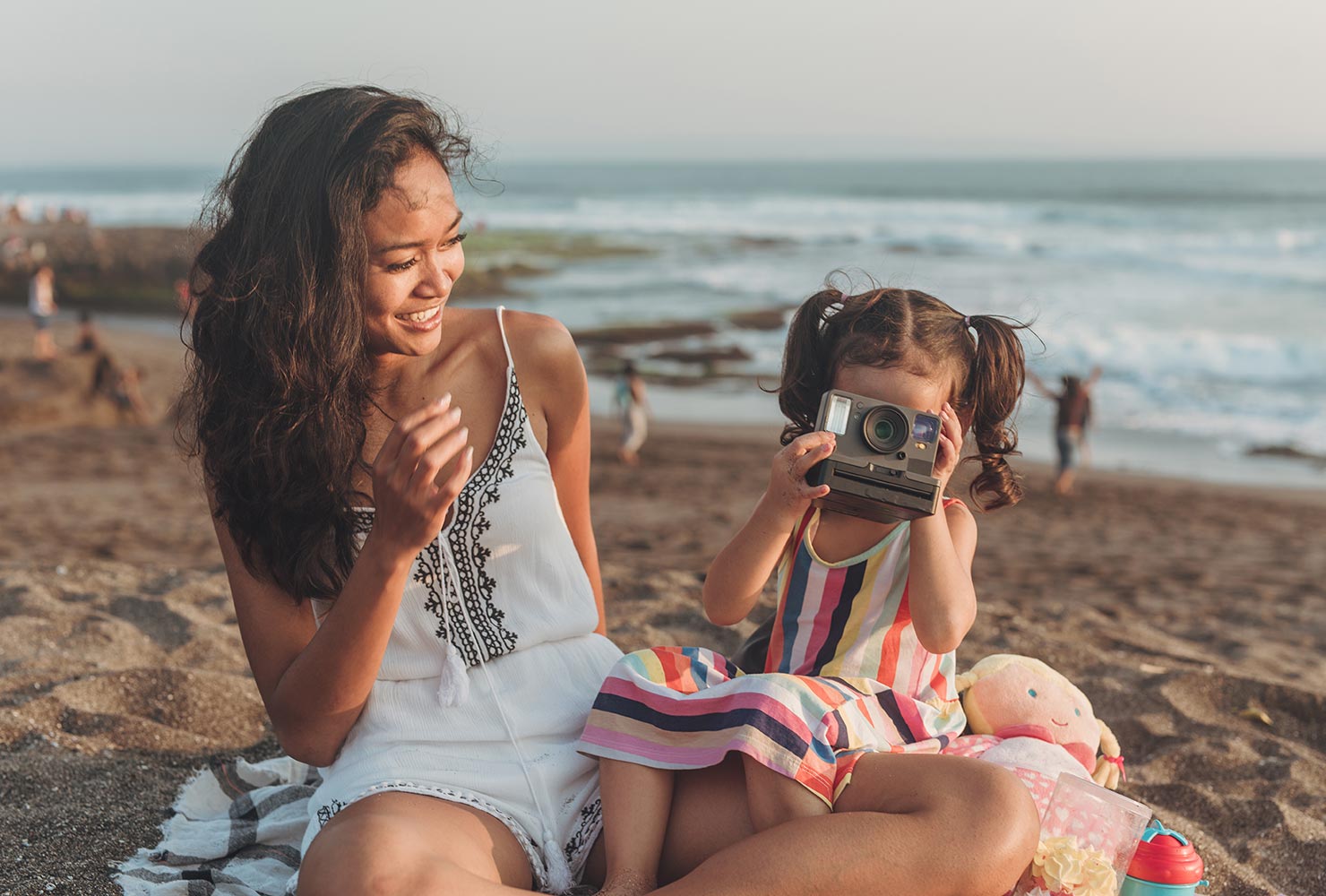 Mother and daughter on beach with camera.