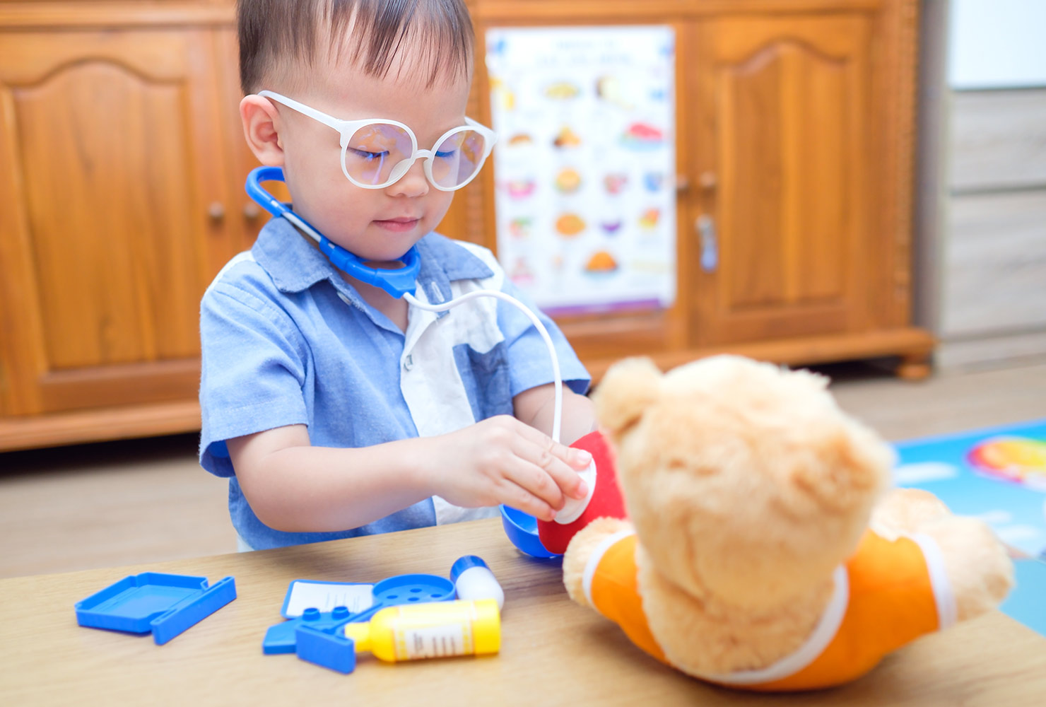 Toddler playing doctor with stuffed bear.