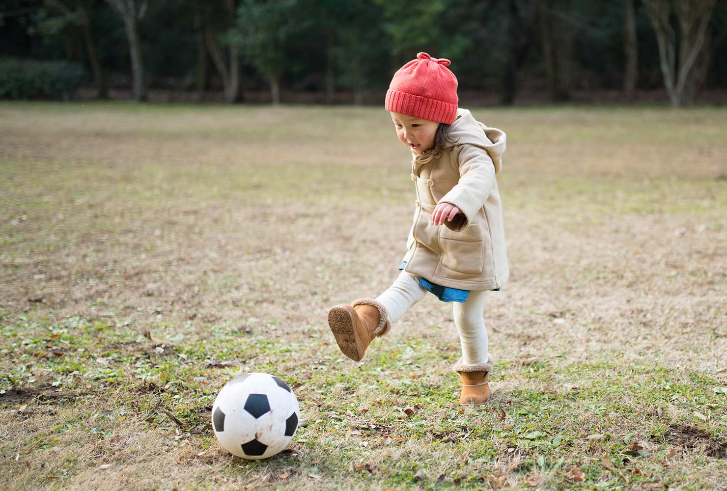 Toddler girl kicking soccer ball.