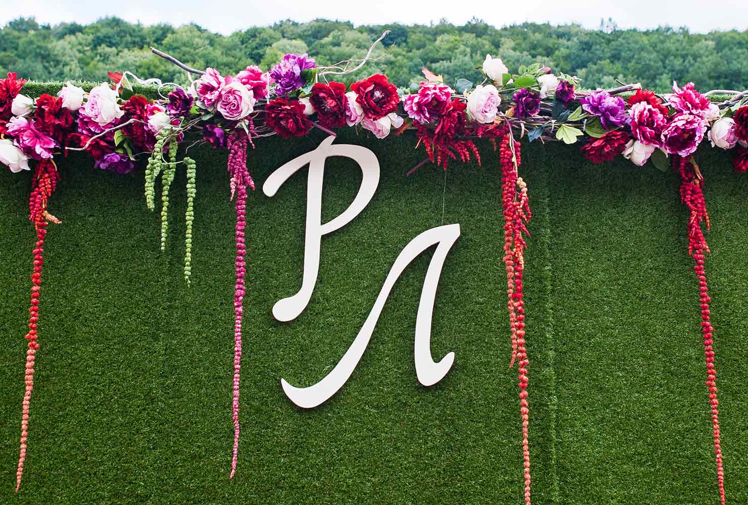 White initials on wedding ceremony backdrop.