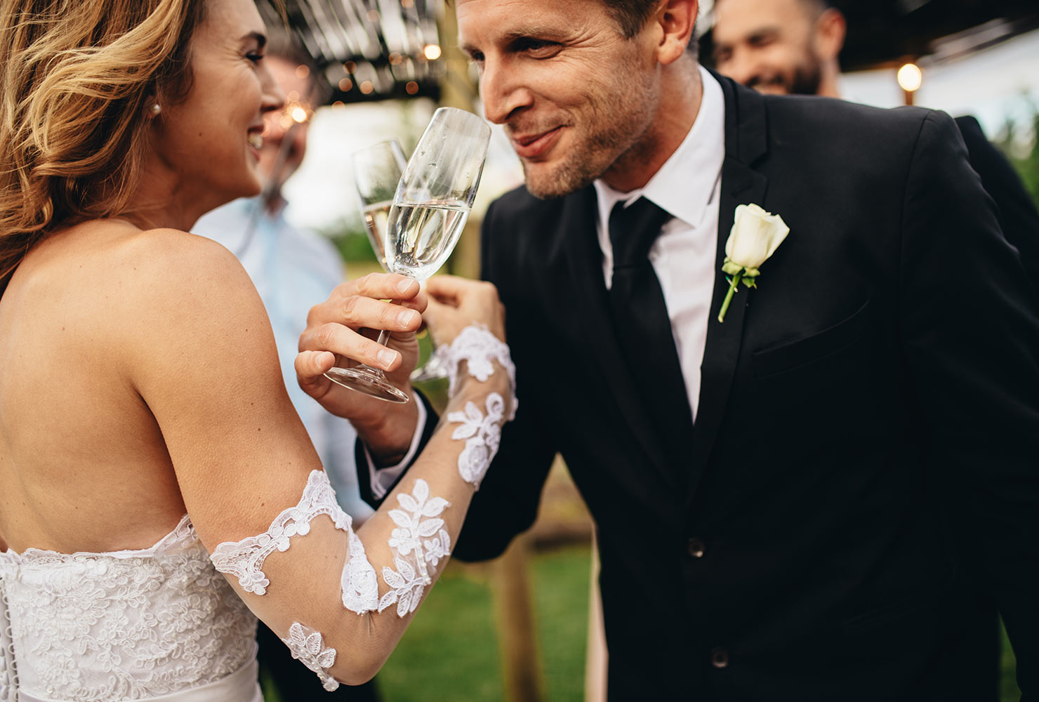 A bridge and groom sip champagne with the arms interlocked. arms