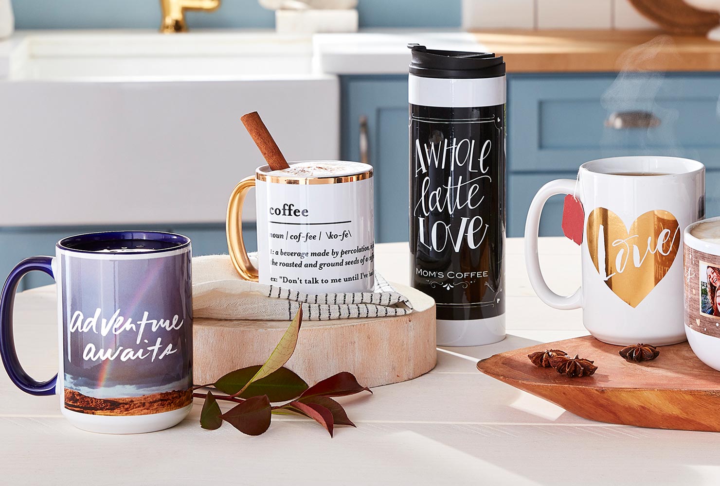 Coffee mugs and tumbler with quotes on table.