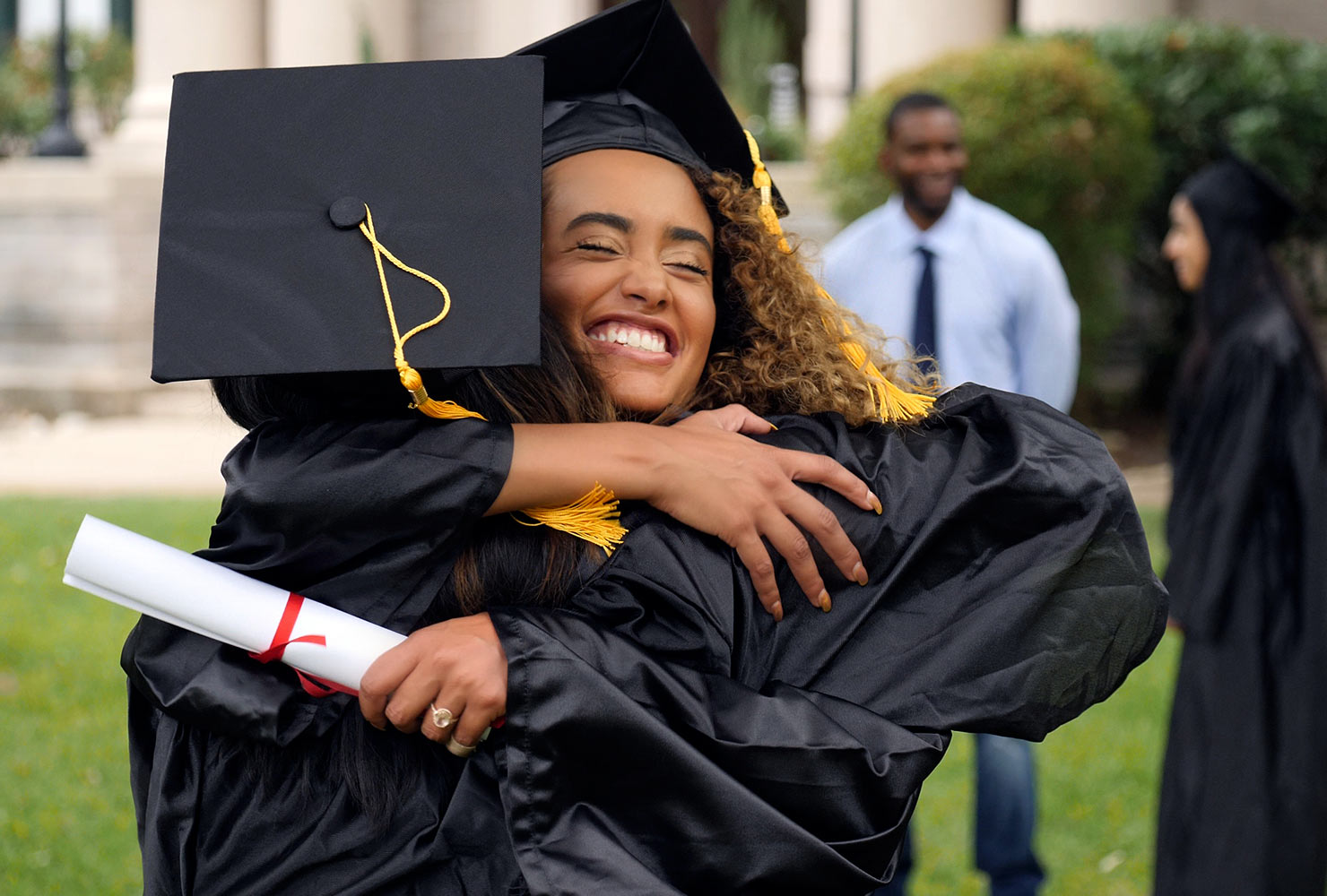 Two girl graduates smiling and hugging