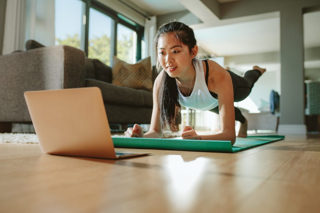 Woman working out at home watching video tutorial on laptop. 