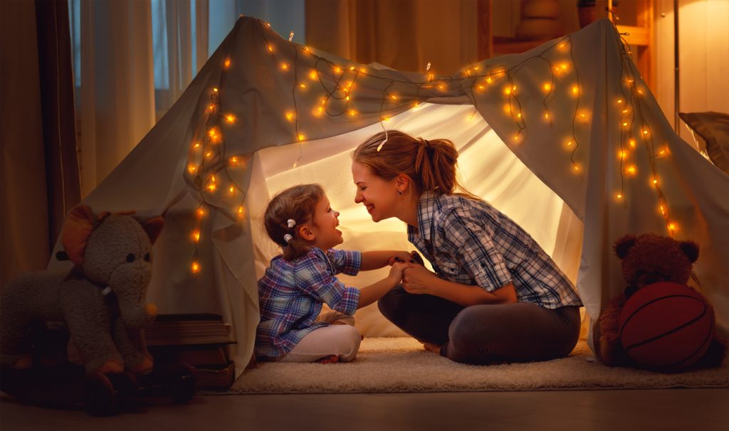 happy family mother and child playing at home in a tent
