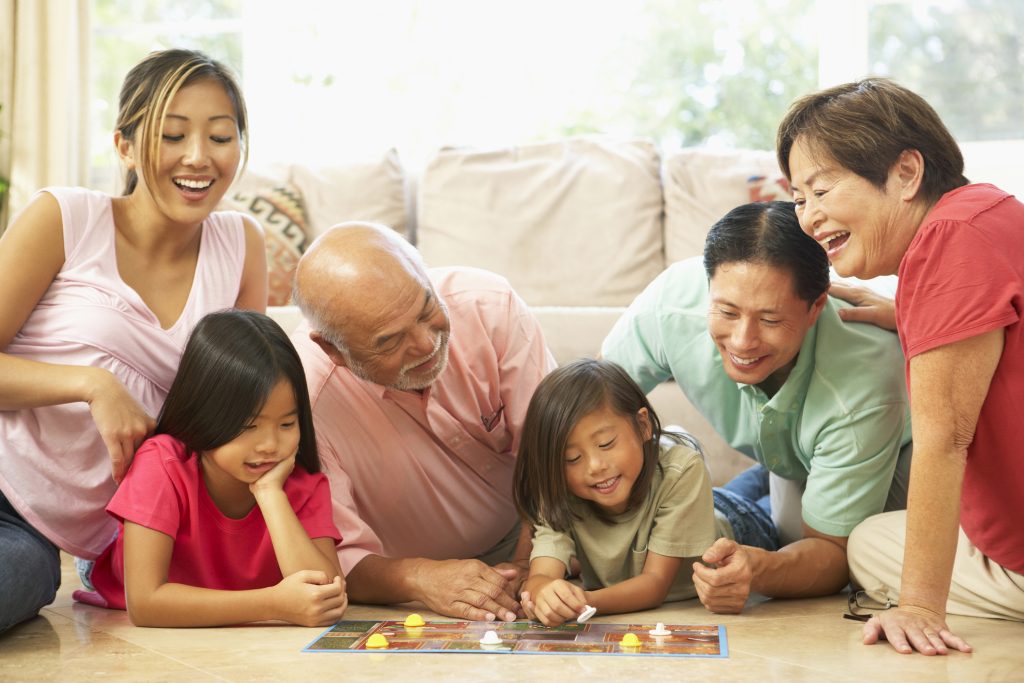 Extended Family Group Playing Board Game In Living Room At Home