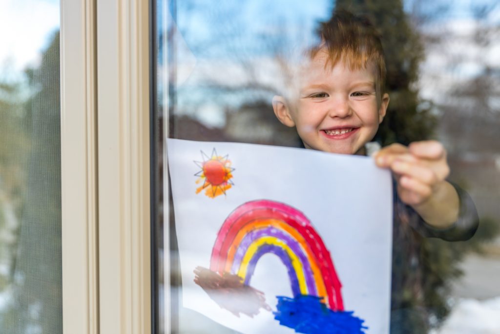 boy showing his art through window