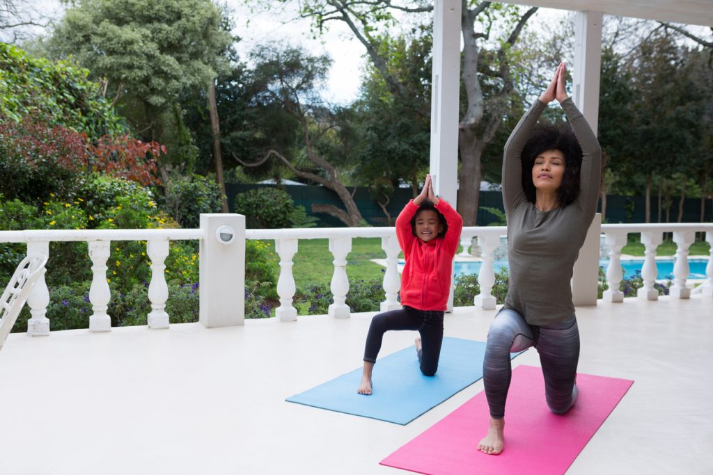 Mother and daughter performing yoga in the porch