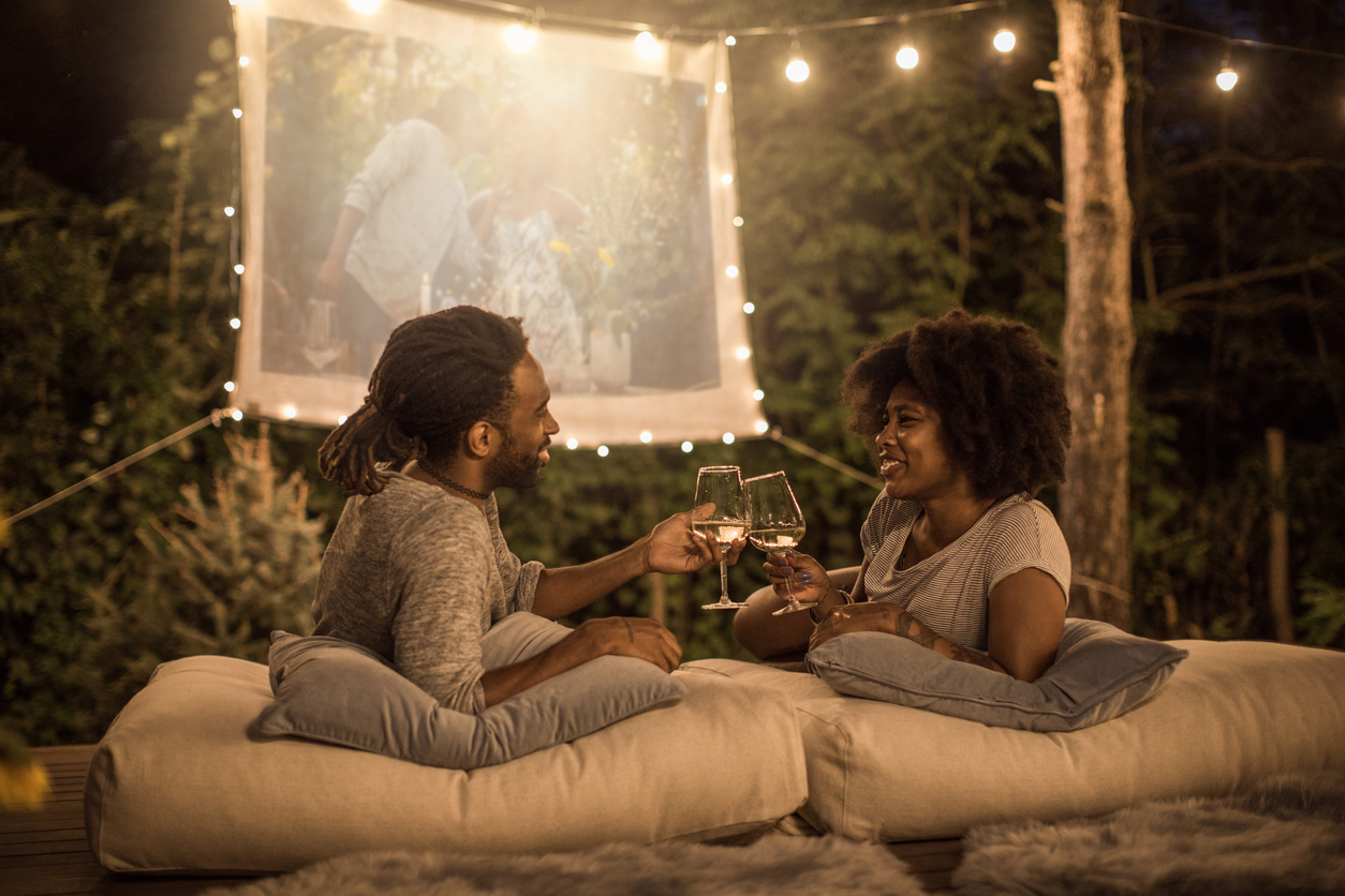 couple having a date night outside watching a movie and drinking wine