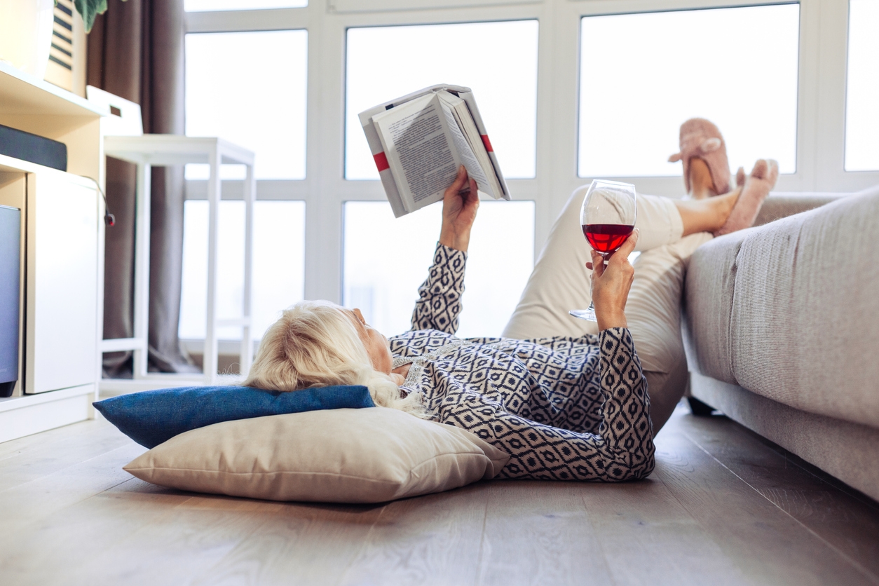 woman lounging reading a book and drinking wine