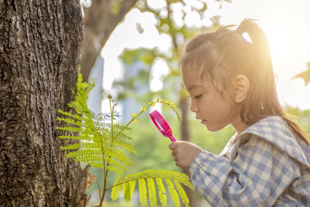 young girl looking at plants in nature
